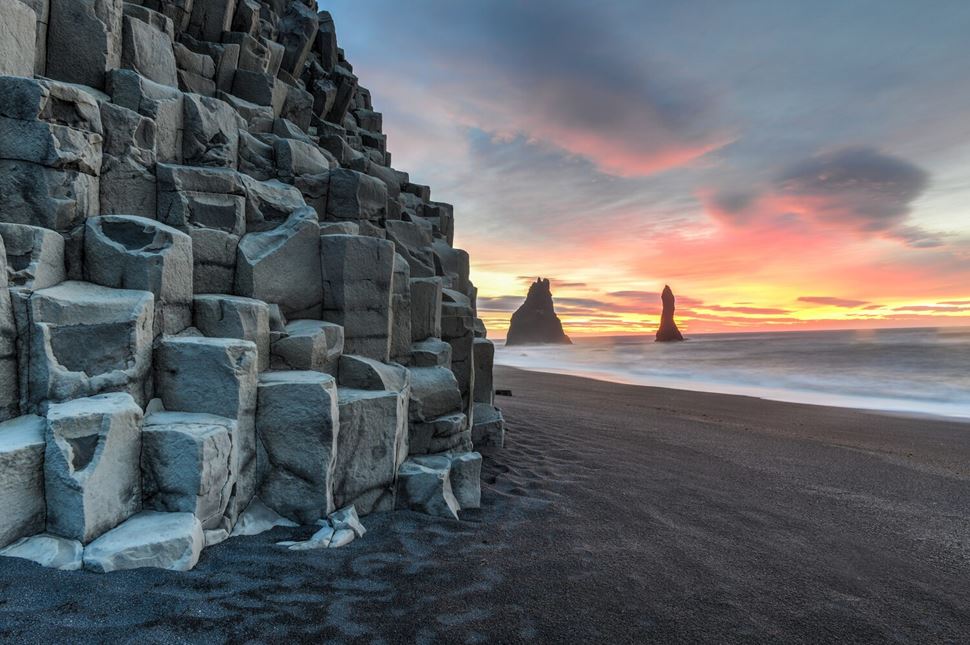 Reynisdrangar on Reynisfjara Beach rock formation in pink sunset by the sea