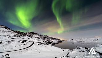 northern lights in winter above a road in iceland