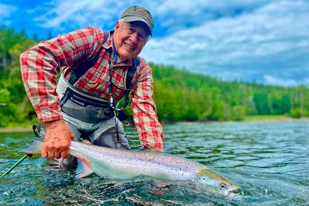 Man with red shirt holding fish in river