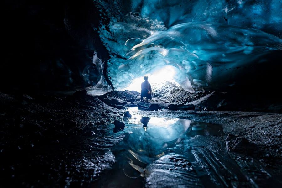 Person crouching down inside blue ice cave at Vatnajokull 