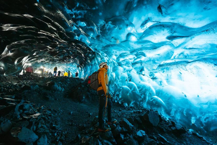 Small group tour inside blue crystal ice cave exploring the cave with safety gear