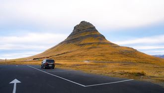 A Car Standing Next To Kirkjufell Mountain