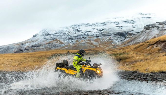 riding atv through a river in iceland