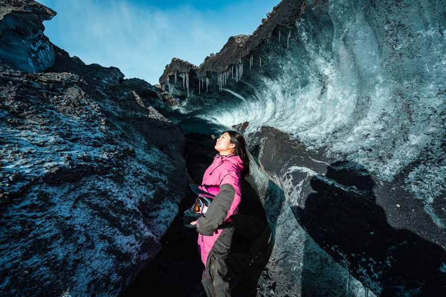 a woman outside of an ice cave in iceland