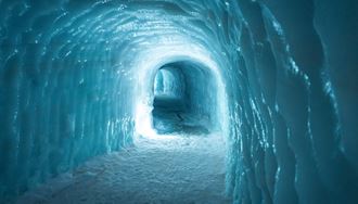 Blue ice walls of Langjokull glacier ice tunnel with light reflecting 