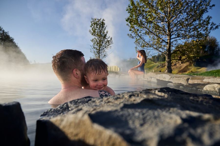 Family in secret lagoon pool, father and child  hugging and mother swimming 