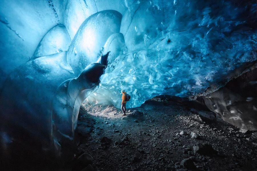 Blue ice cave walls with beautiful bubble wall pattern and tourist posing