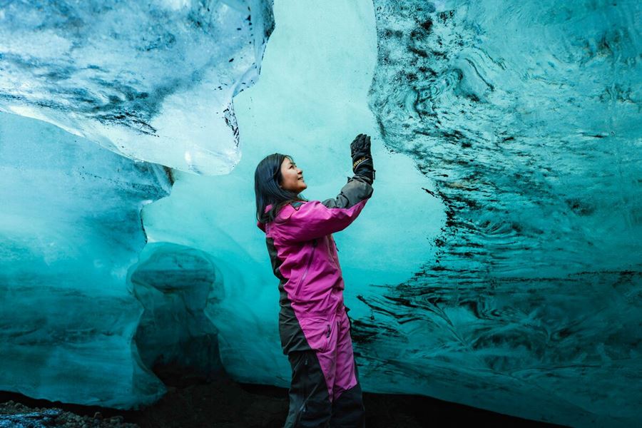 a woman touching ice caves walls