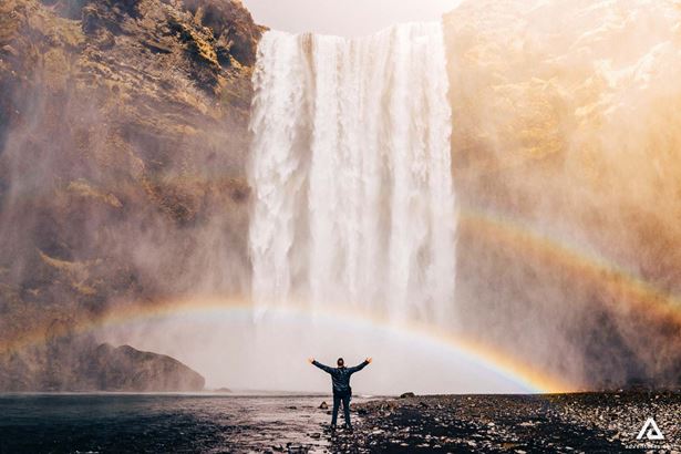 Raised hands person standing in front of a Skogafoss waterfall
