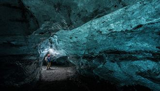 Inside Blue crystal ice cave with reflecting light shining onto ice cave walls at Vatnajokull, 2025.