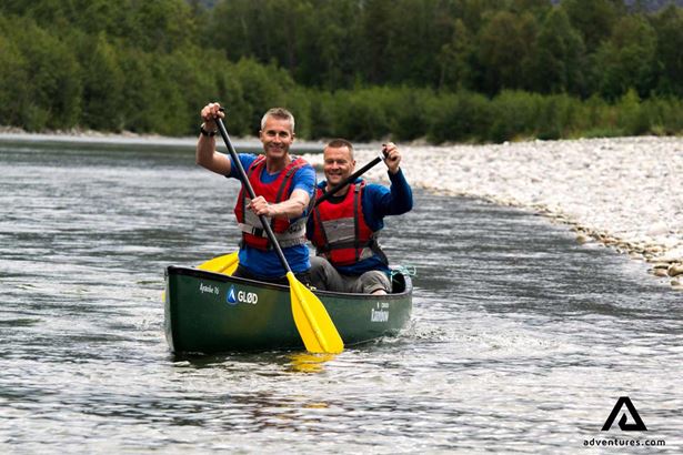 two happy friends canoeing in river