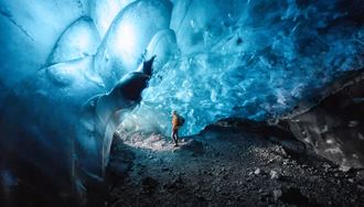 Blue ice cave walls with beautiful bubble wall pattern and tourist posing