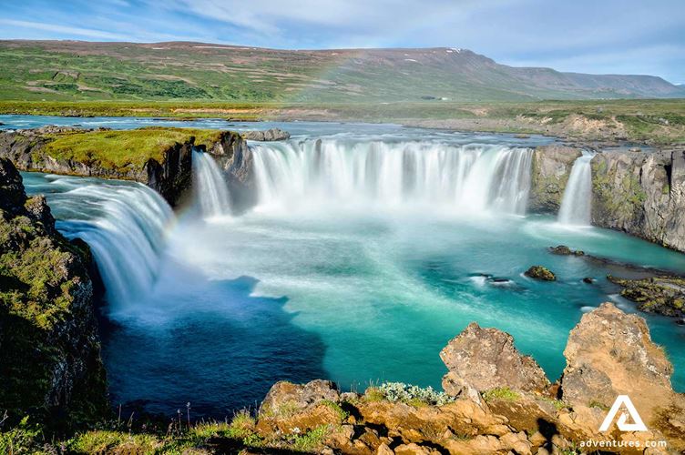 small rainbow over godafoss waterfall in north iceland