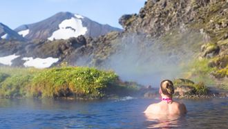 View of back of female tourist bathing in hot springs Landmannalaugar