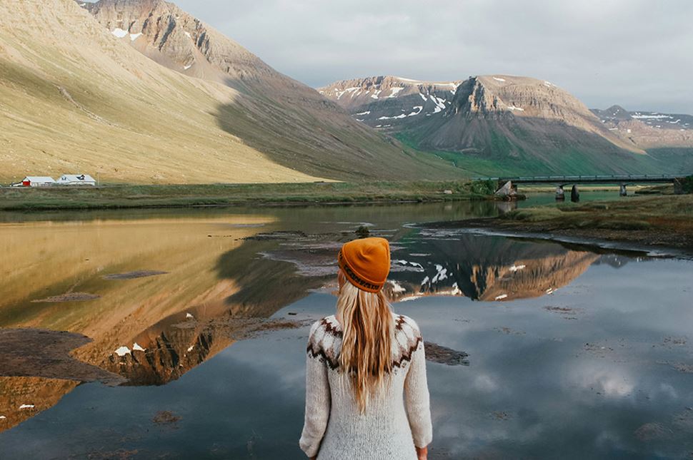 Woman autumn clothes looking over mountain landscape in Icelandic Fjords