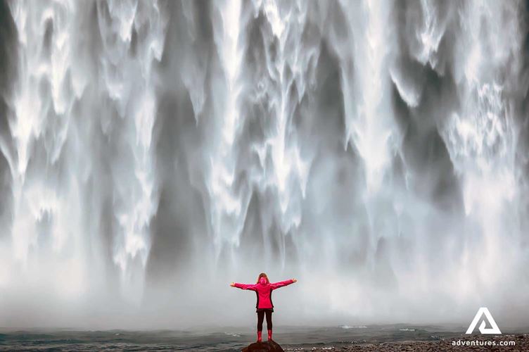 woman near a powerful waterfall Skogafoss