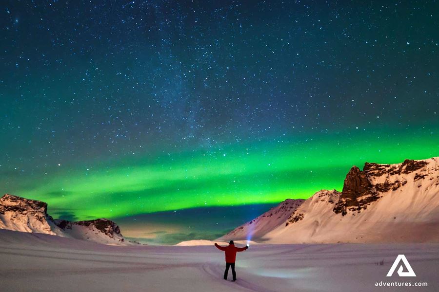 man with a flashlight watching northern lights